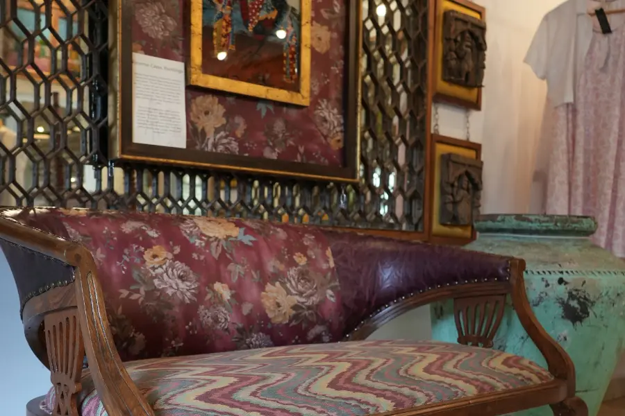 View of a vintage wooden sofa with patterned fabric and antique décor in a luxury interiors showroom.