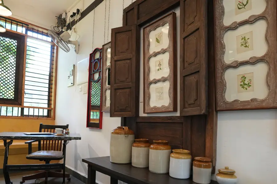 View of an old wooden cabinet with open shutters and ceramic jars arranged on a table in a heritage-style interior.