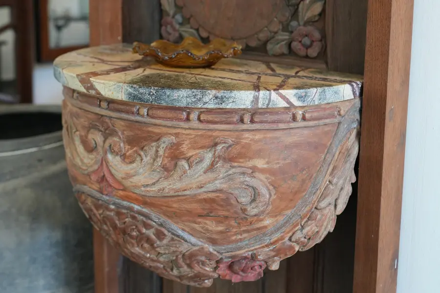 View of a carved antique wooden wall shelf and decorative detailing in a traditional interior.