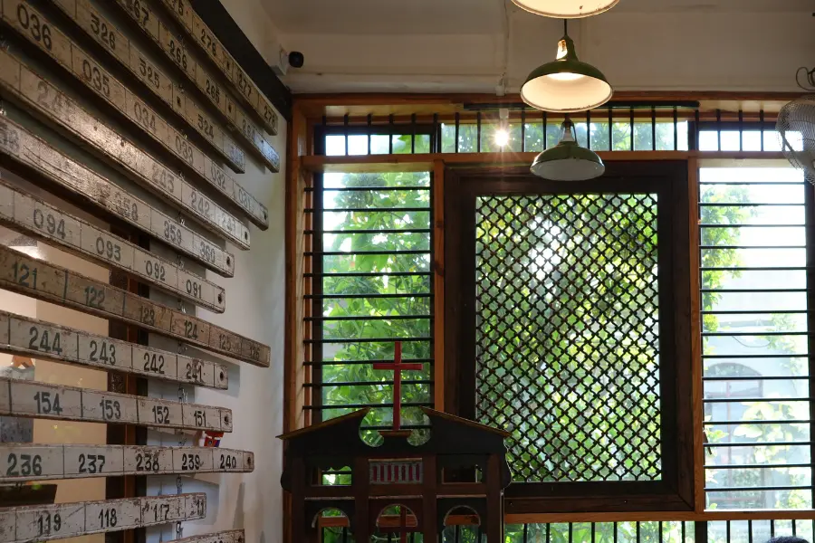 View of a sunlit vintage interior with wooden windows, hanging lights, and restored antique furniture.