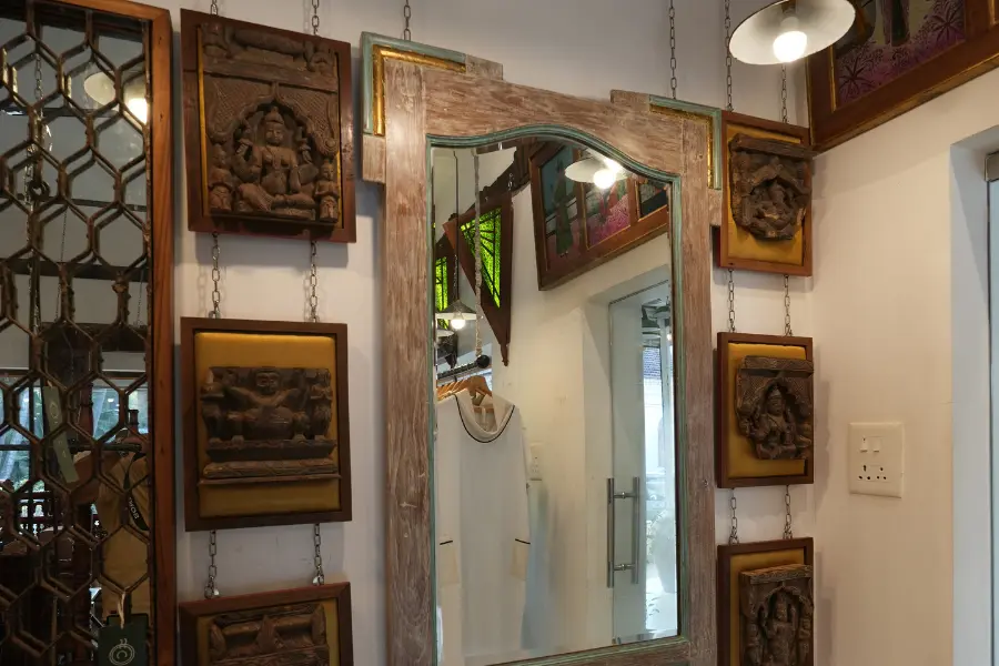 View of an antique wooden mirror surrounded by carved panels and traditional wall décor.